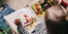A young human child views a book with a picture of a cartoon fox upon it.