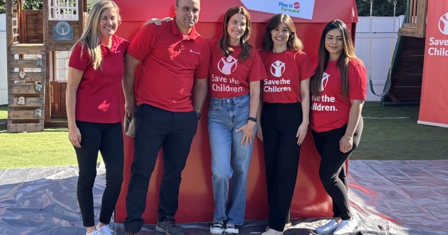 Volunteers, including actor Cobie Smulders, posing in front of a big red box.