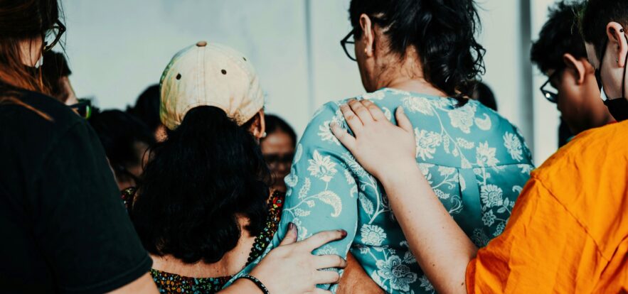 A picture from behind of a group of people with their arms on each other.