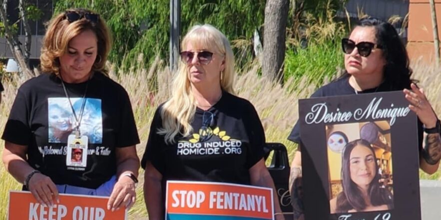 Three women hold signs opposing fentanyl.